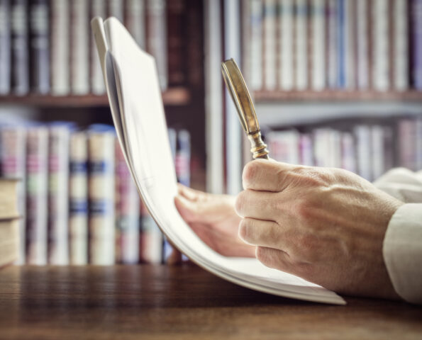 Businessman reading documents with magnifying glass concept for analyzing a finance agreement or legal contract