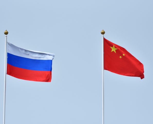 China and Russia flag waving in the wind against white cloudy blue sky together. Diplomacy concept, international relations.