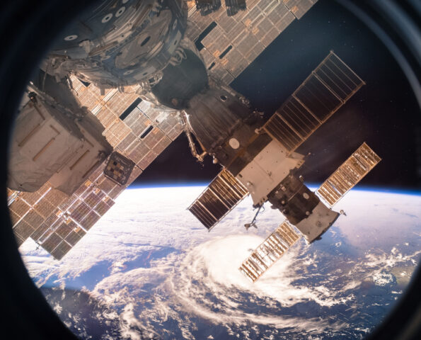 An image of a satellite seen from space, with Eath in the distant background.