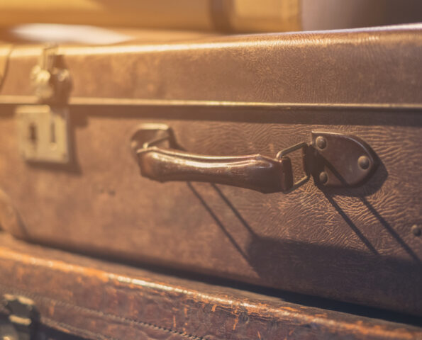 A closeup image of the handle of a brown, vintage suitcase. It is filtered with a sepia tone.