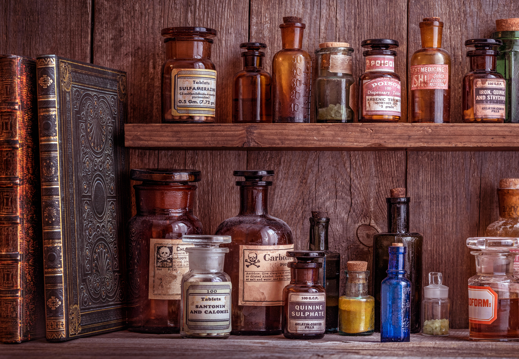 A wooden shelf with antique glass bottles. The bottles contain various medicines, poisons, and chemicals.
