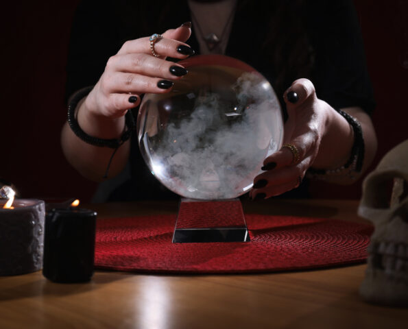 Soothsayer using crystal ball to predict future at table indoors, closeup